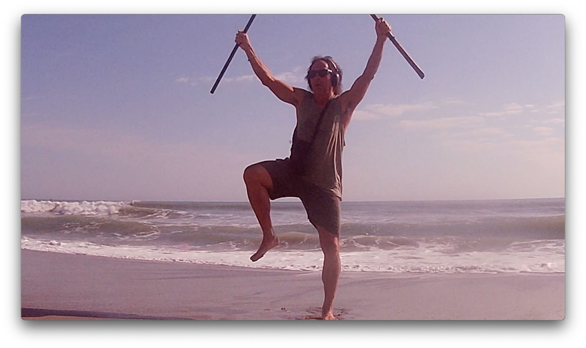 A man dancing with two sticks at the surf line on Cocoa Beach